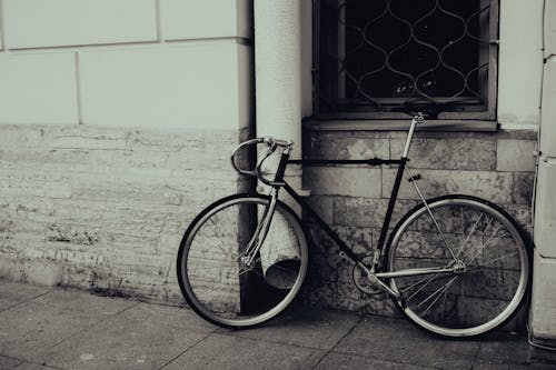 Grayscale Photo of Bike Leaning on Wall