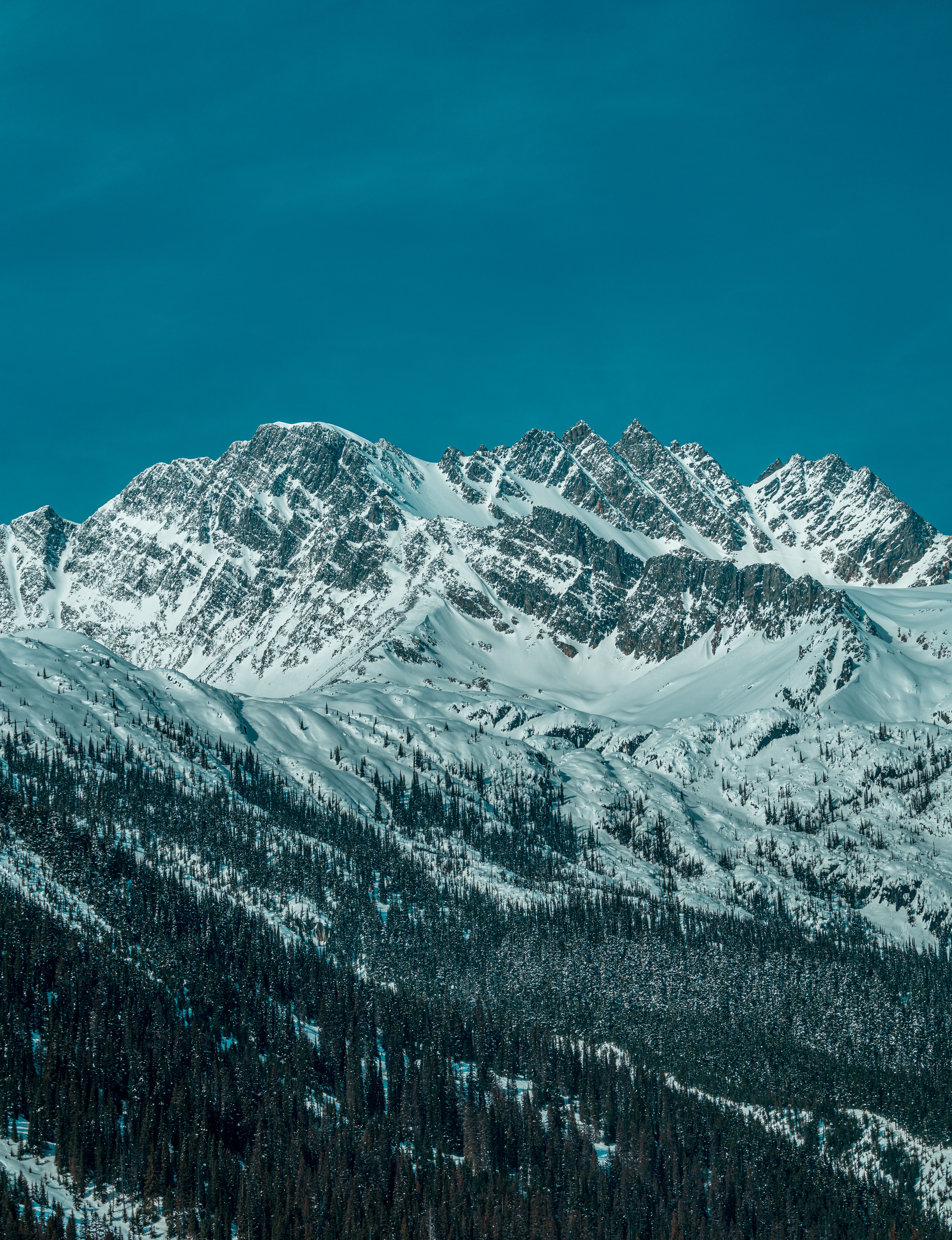 A breathtaking view of snow-covered mountain peaks under a clear blue sky, capturing winter's serene beauty.
