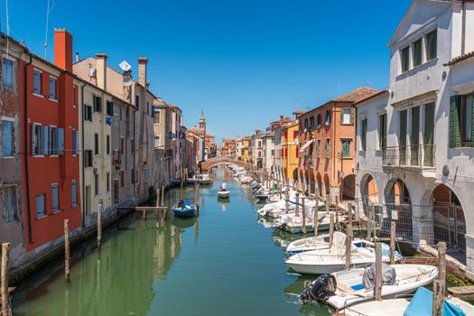 Colorful houses and boats line a picturesque canal in Chioggia, Italy.