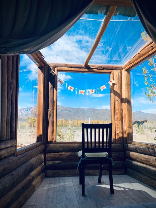 Free A wooden chair inside a rustic cabin with a breathtaking view of the Andes Mountains in Uspallata, Argentina. Stock Photo