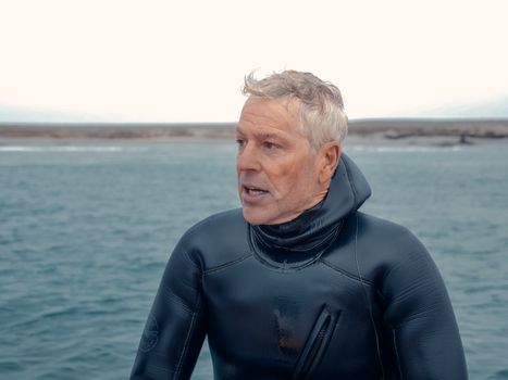 A seasoned diver in a wetsuit gazes over the ocean, capturing the essence of water adventure.