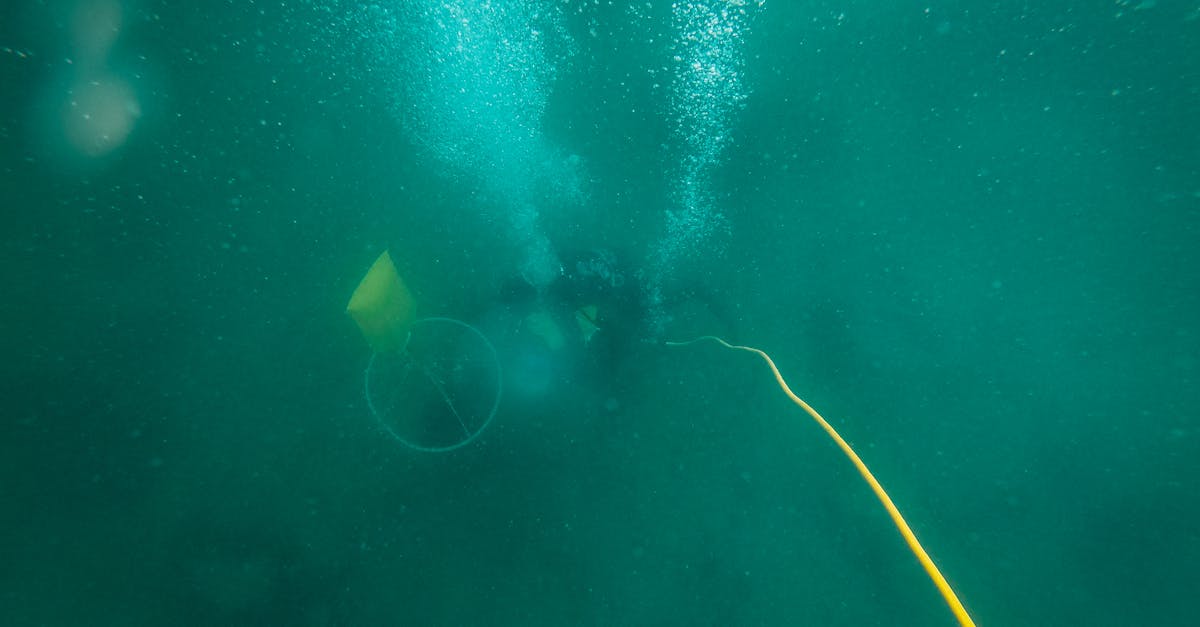 A diver explores underwater depths with bubbles rising in the turquoise ocean water.
