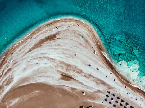 A breathtaking aerial shot of a sandy beach with turquoise waters, showcasing beachgoers and umbrellas.