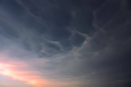 Free Dramatic mammatus clouds hang in a twilight sky with a soft sunset glow, creating a captivating natural scene. Stock Photo