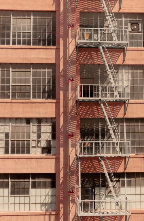 Free Fire escape stairs on a brick apartment building with grid windows. Stock Photo