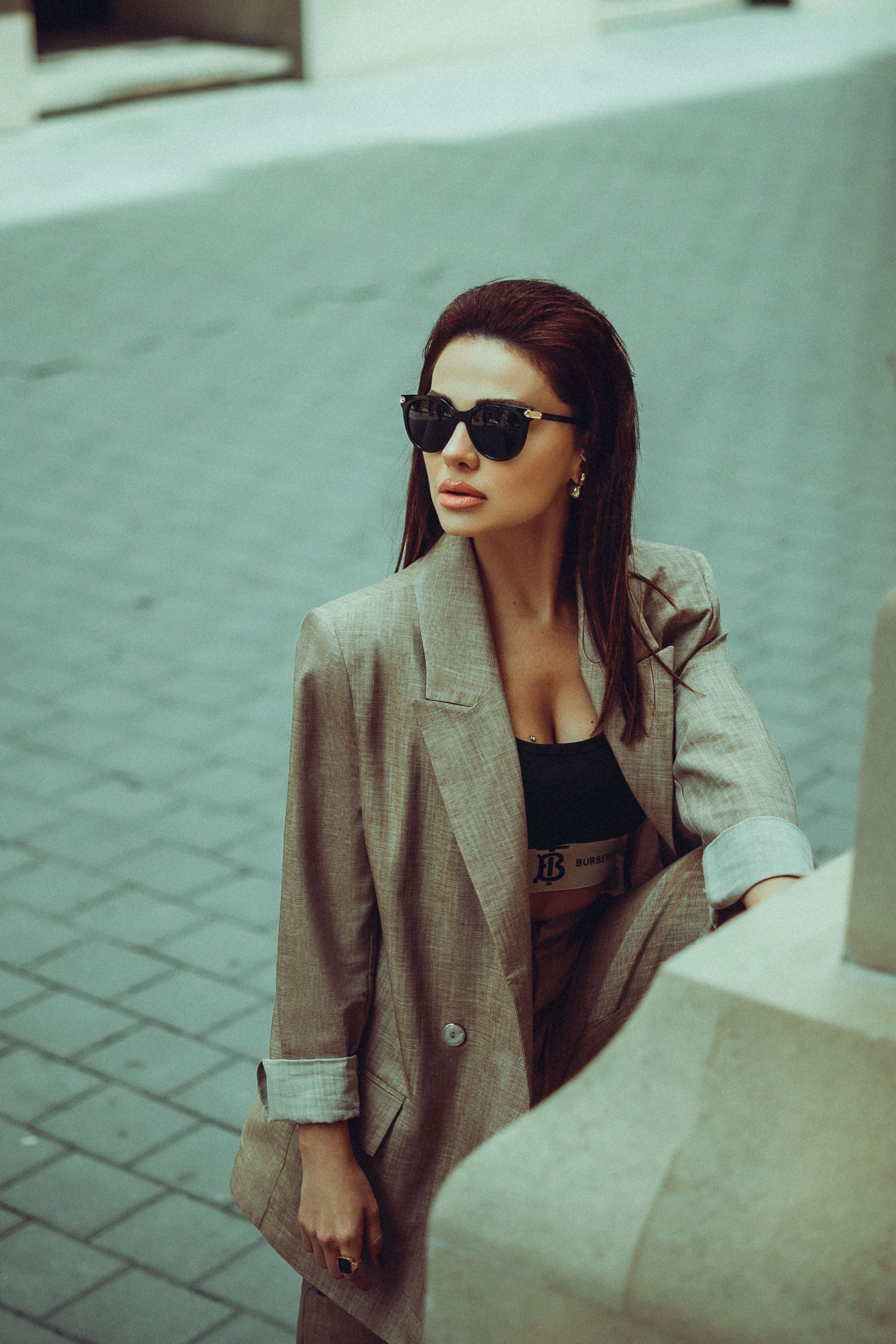 Fashionable woman in a stylish blazer with sunglasses posing outdoors.