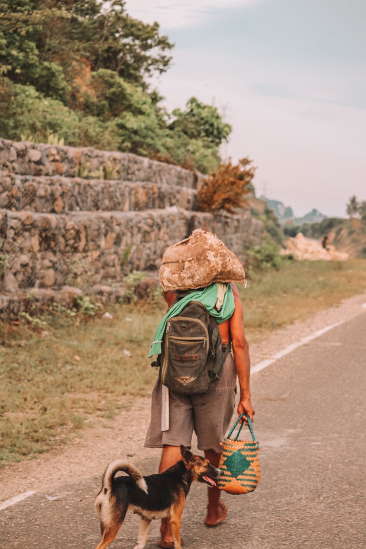 Man Carrying Luggage Along A Country Road