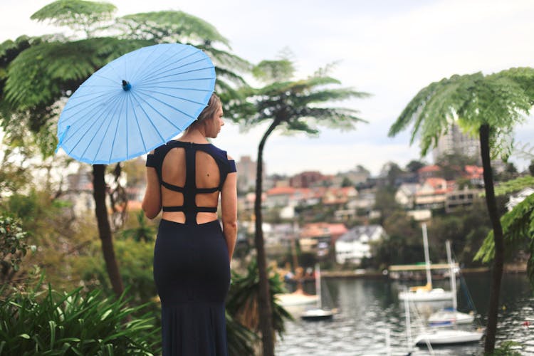 Back View Of A Woman In Dress Holding Blue Umbrella 