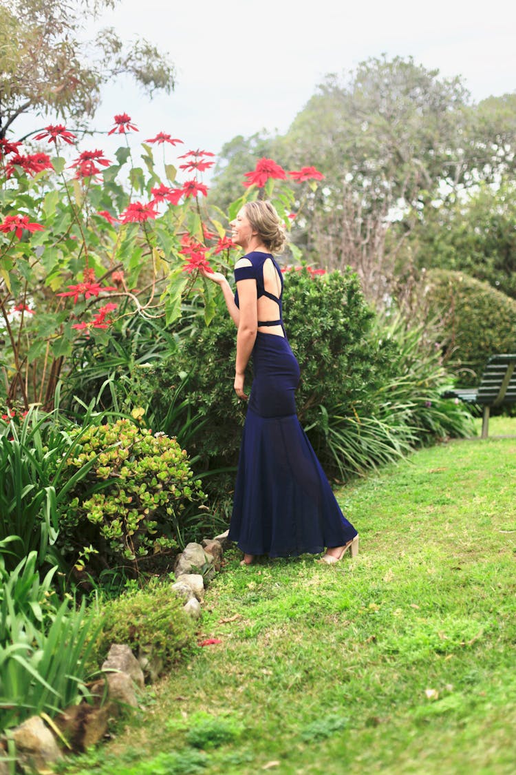 Woman In An Elegant Dress Smelling Flowers In The Garden 