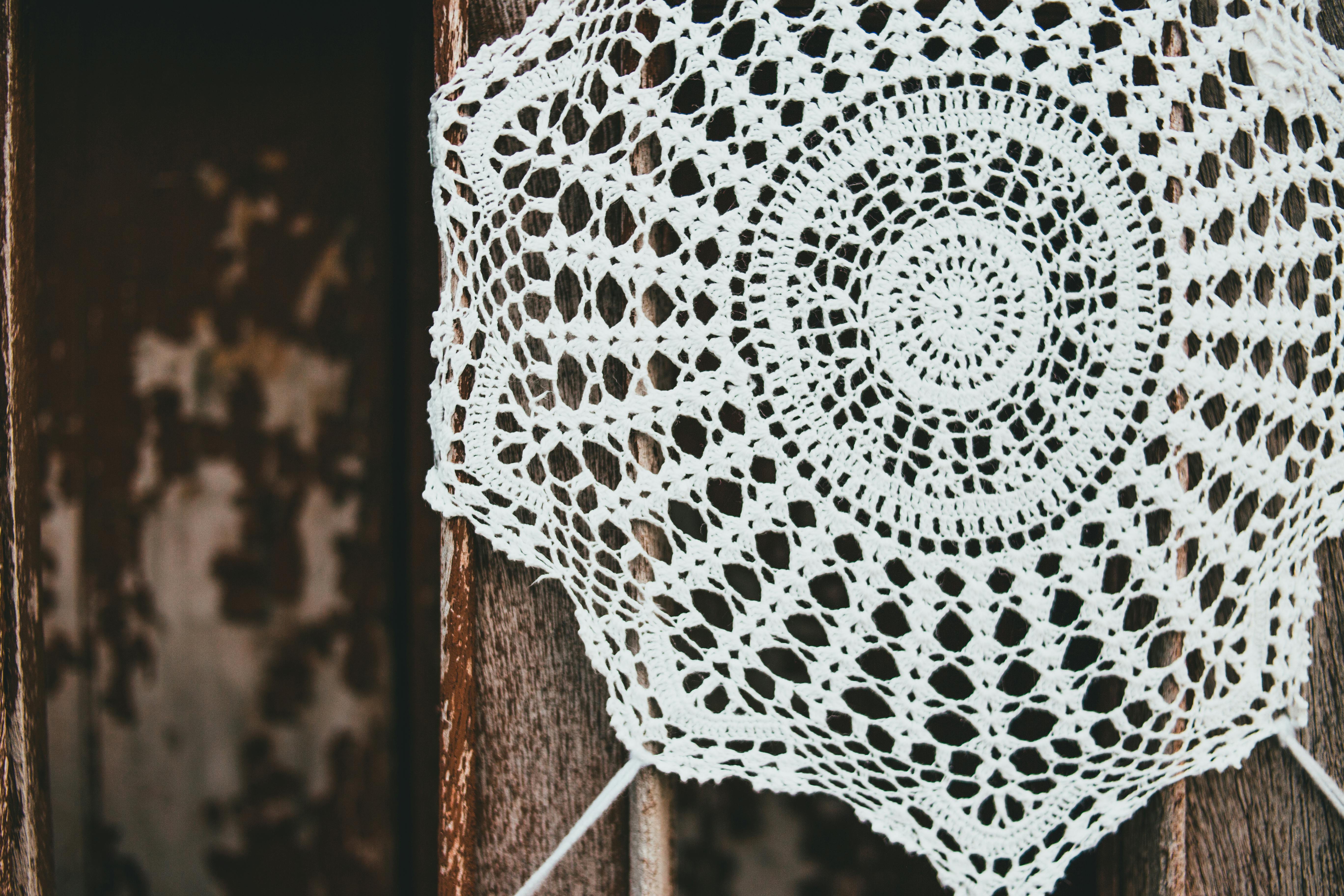 Delicate handmade crochet doily featuring an intricate design set against a rustic wooden background.