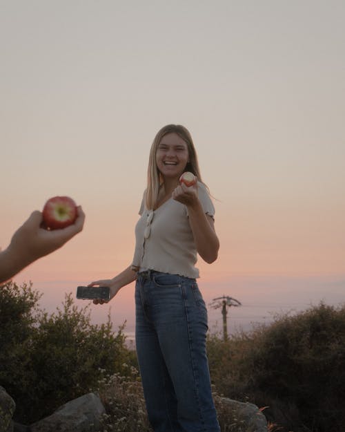 A Woman Smiling while Holding an Apple