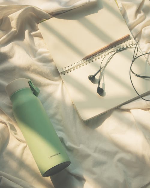 Free Water Jug and Notebook on White Linen Stock Photo