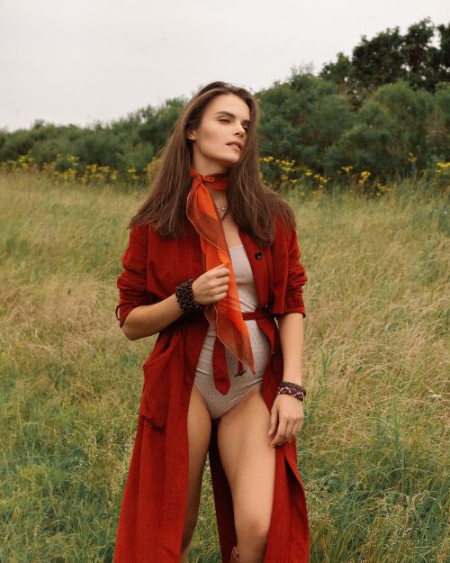 Free Fashion shot of a woman in a red coat posing in a field, showcasing outdoor style. Stock Photo
