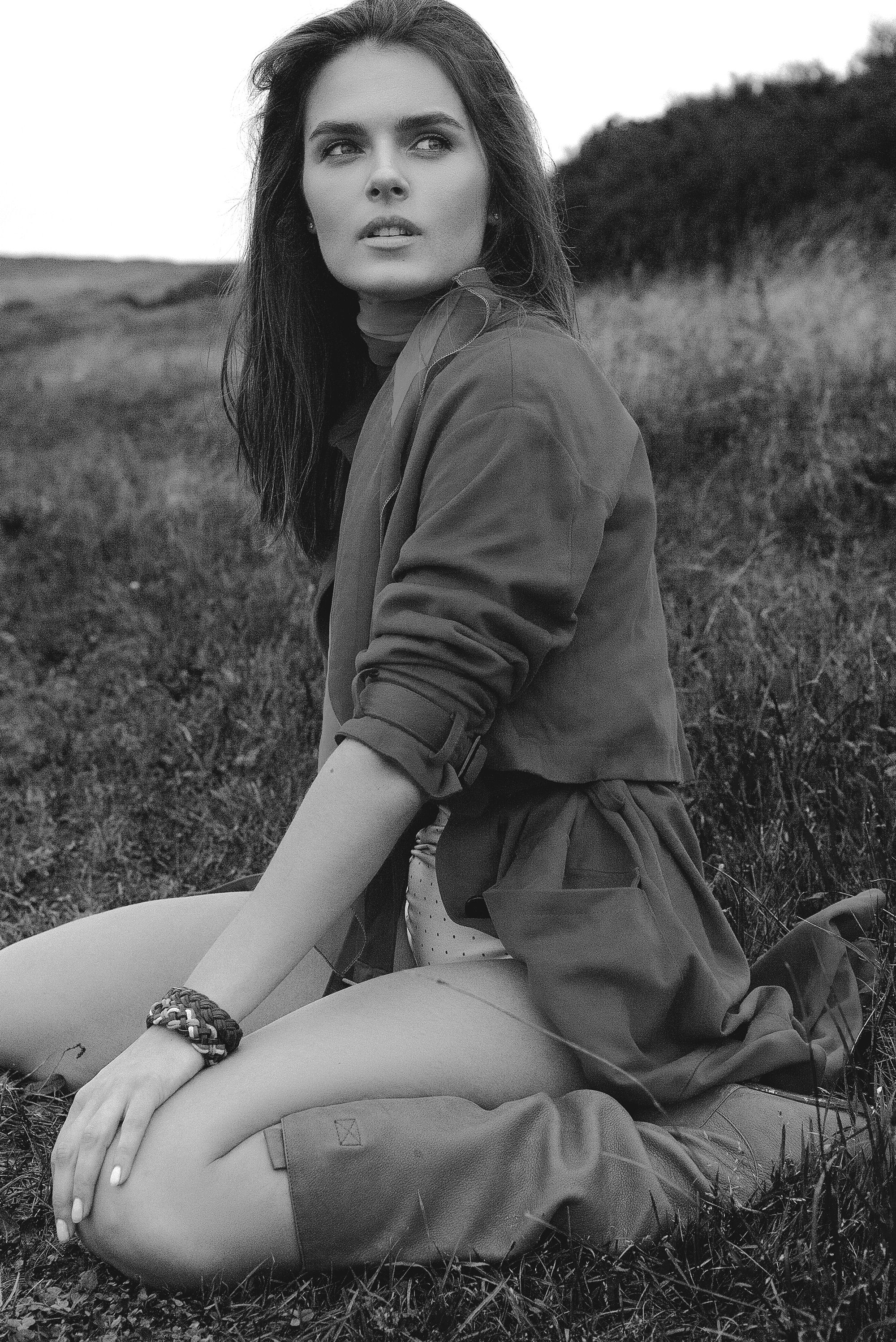 A striking black and white portrait of a woman seated outdoors, evoking elegance and style.