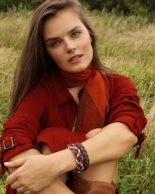Free A woman poses in an autumn outfit sitting in a grassy field, exuding natural beauty and elegance. Stock Photo