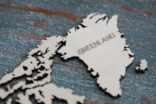 Detailed wooden cutout of Greenland map on textured surface.