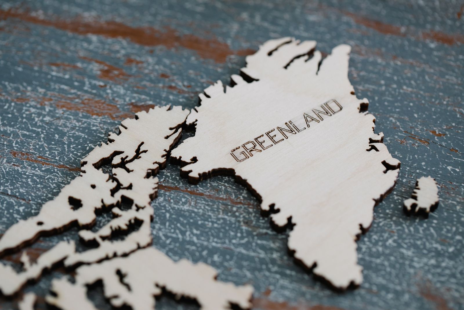 Detailed wooden cutout of Greenland map on textured surface.