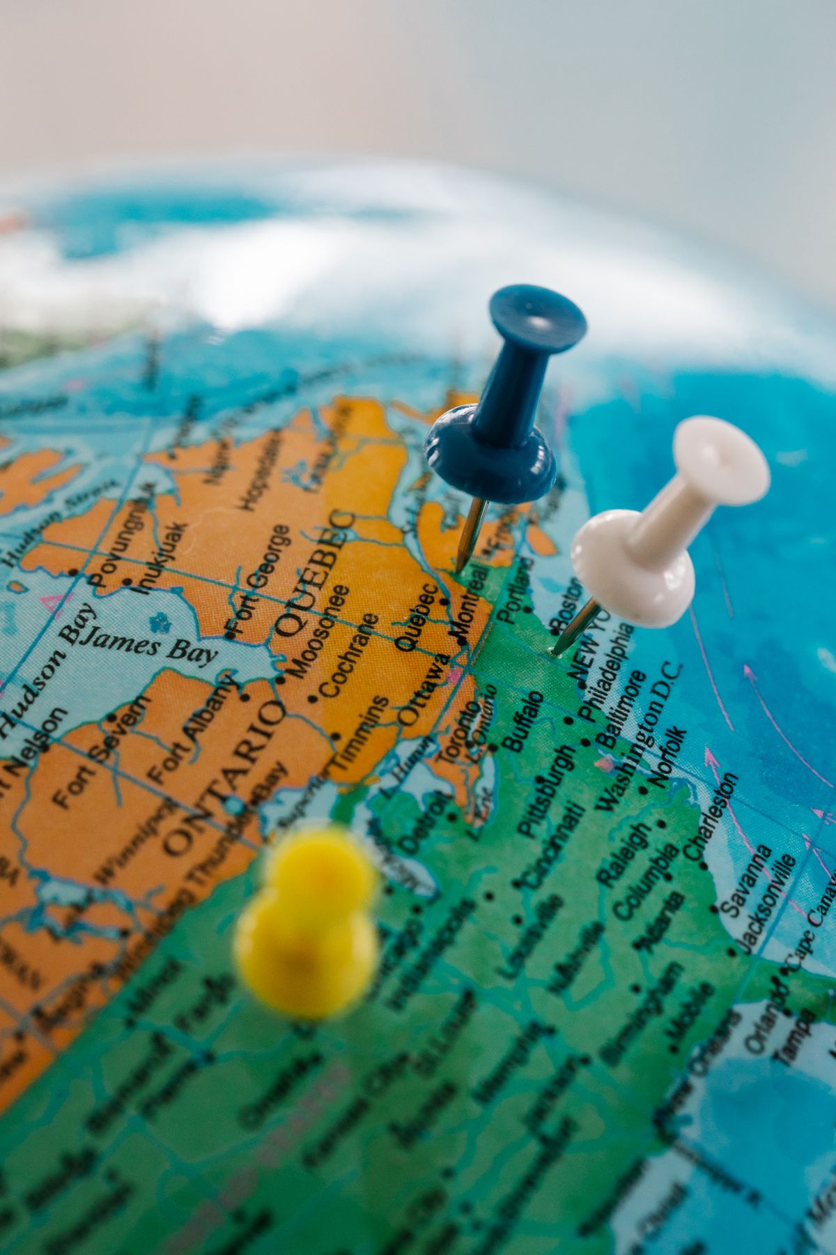 Blue, white and yellow pushpins on a globe around Ontario, Quebec and the northeastern US