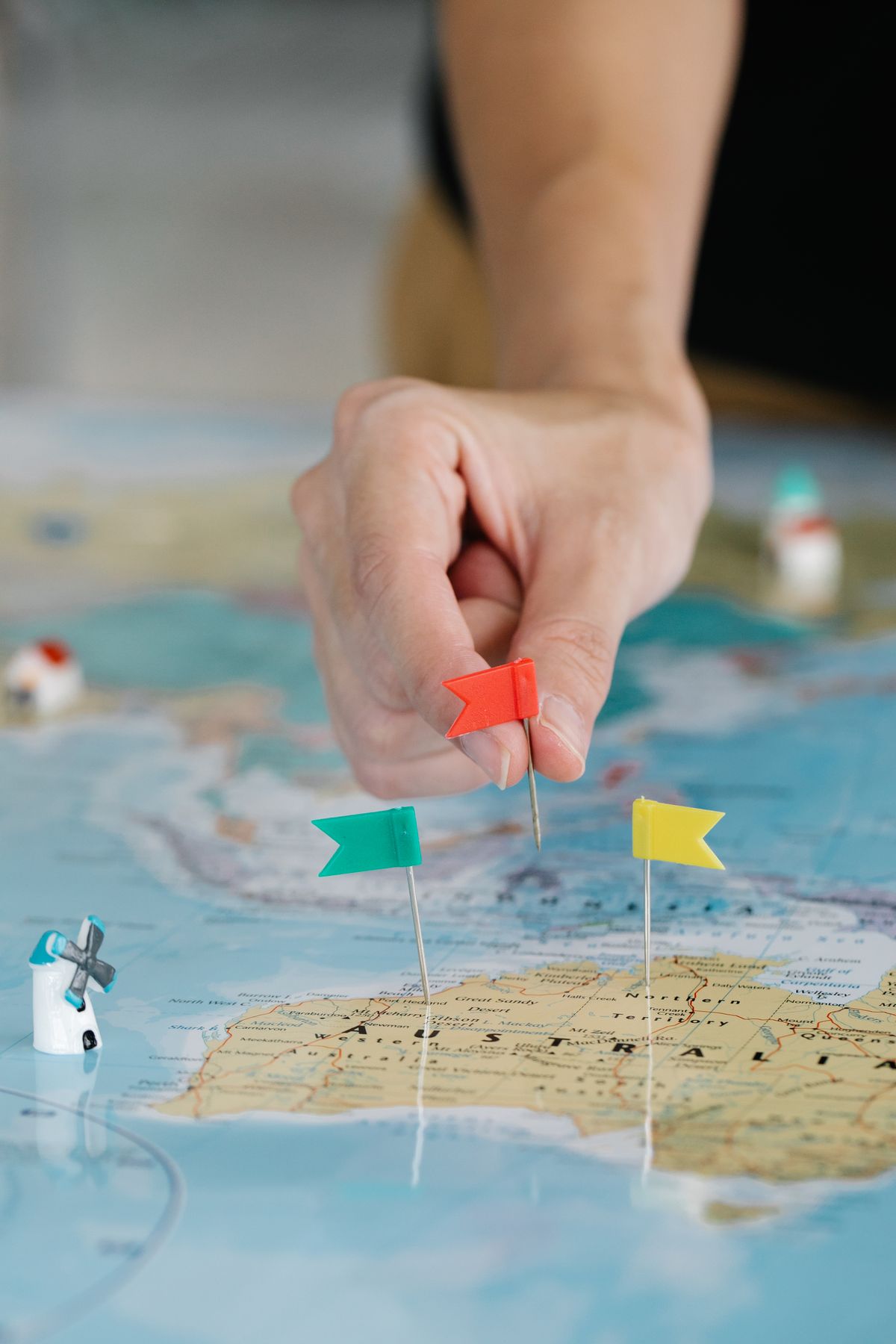 A hand planting a tiny red flag on a map