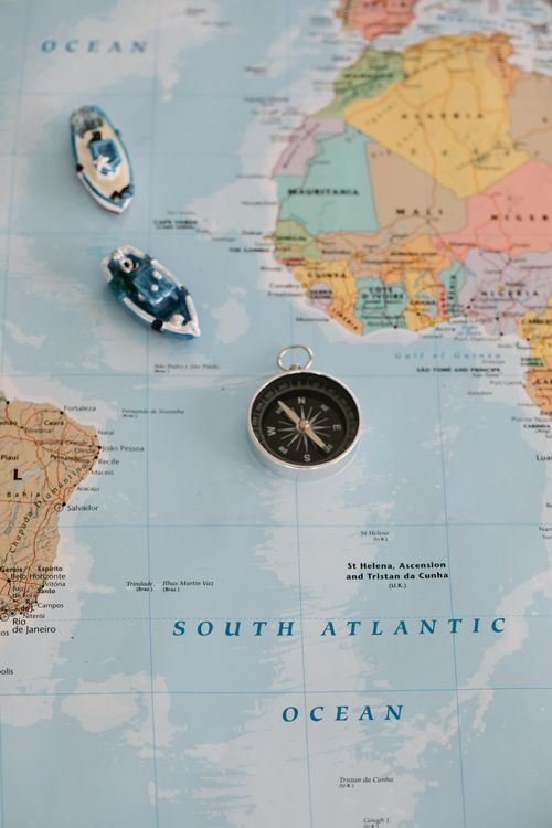 Free A pocket compass lying on a map of the South Atlantic Ocean with two blue toy ships nearby. Stock Photo