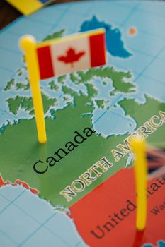 Detailed close-up of a Canadian flag standing on a map of North America, highlighting Canada.
