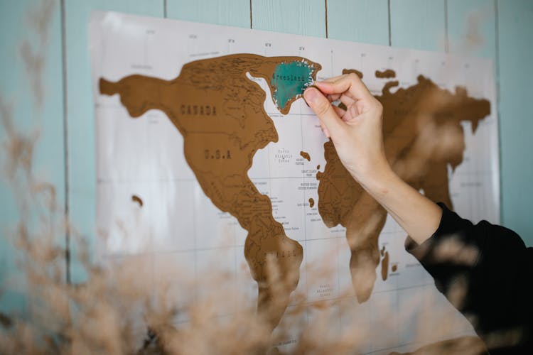 Hand Hand Scratching The Hanging Map On The Wall  