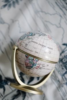 Classic vintage globe captured on a detailed patterned fabric, showcasing world geography with a timeless appeal.