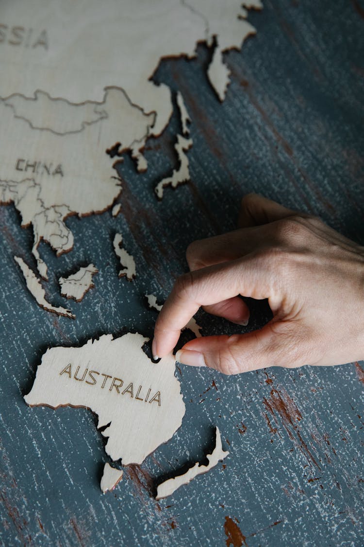 Person Holding Wooden Puzzles In Shape Of Continents And Countries 