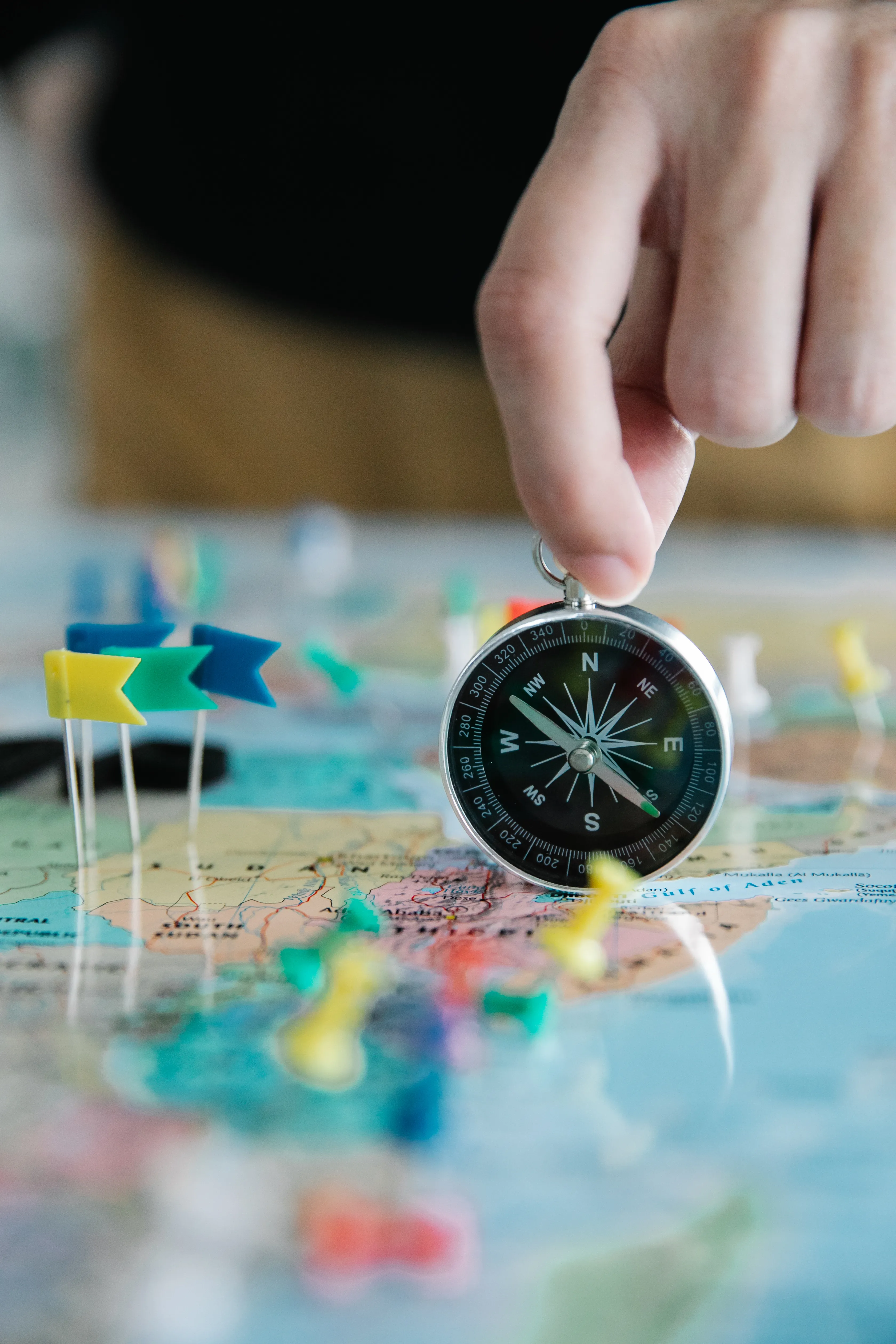 A hand holding a compass over a paper map