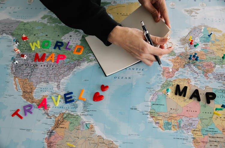 Unrecognizable Person Planning Travel On World Map