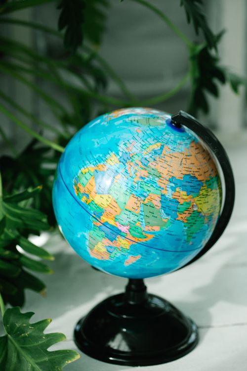 Free Vibrant globe on a stand surrounded by lush green plants. Stock Photo