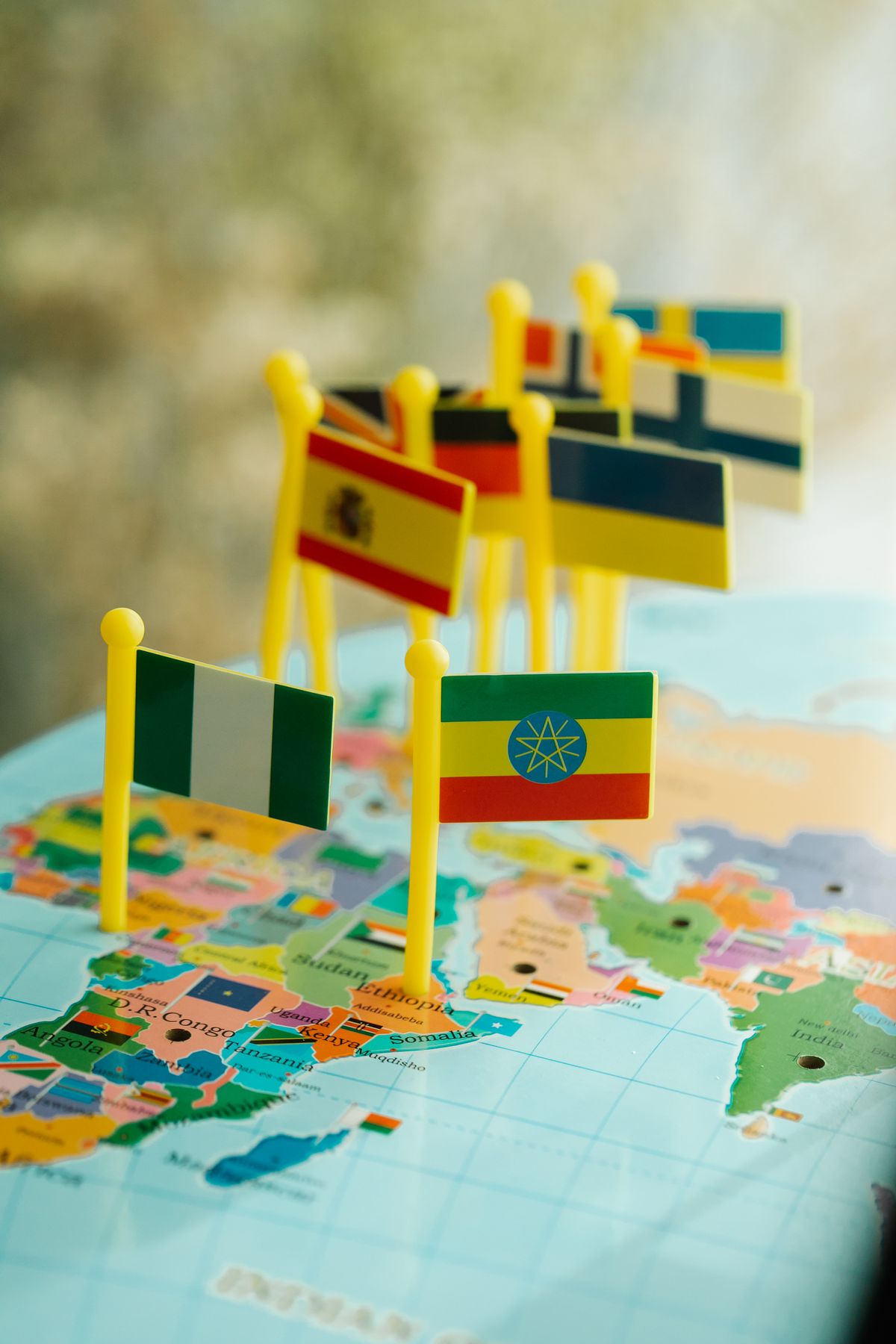 Small flags pinned on a colorful world map, marking countries