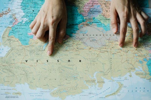 Close-up of hands pointing at Russia on a detailed world map.