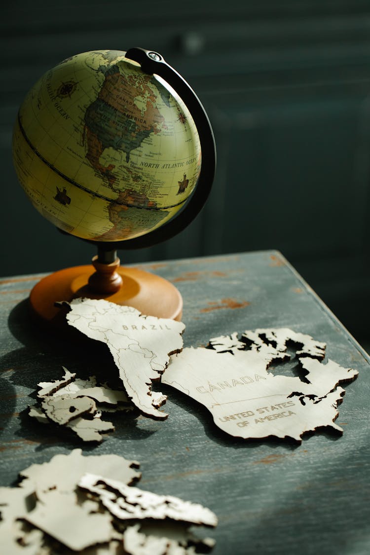 Globe And Puzzle Pieces On A Wooden Table