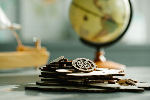 Free Artistic shot of wooden puzzle pieces with a globe in the background, symbolizing navigation and exploration. Stock Photo