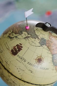 Detailed view of a globe marked with a flag pin indicating North Pacific travel destination.