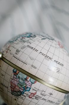 Close-up of a globe highlighting the North Pacific Ocean area, captured vertically. 8828673