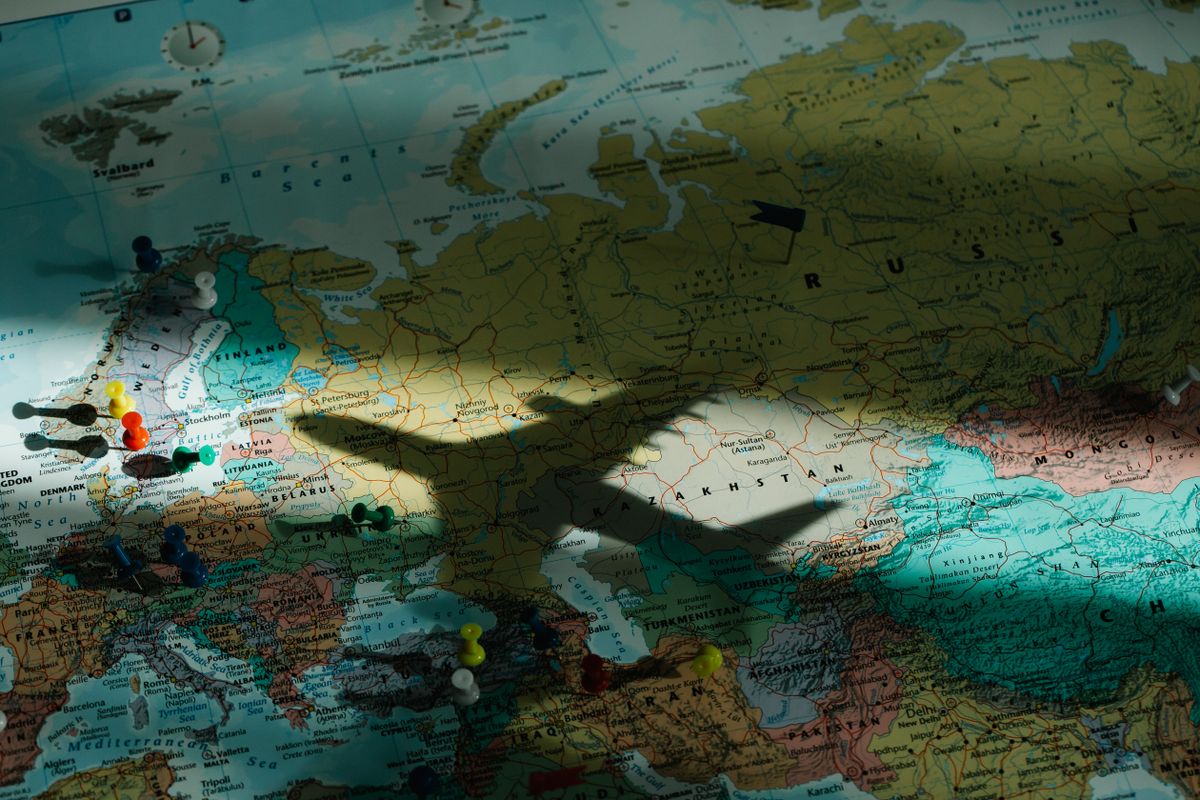 Umbra unui avion trecând peste o hartă a Europei cu pioneze colorate