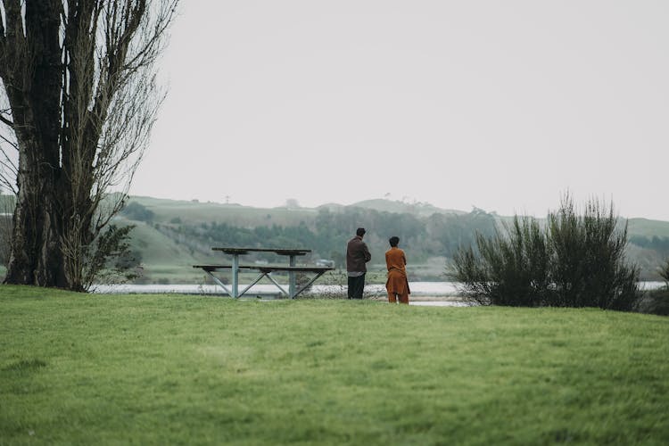 Men Standing On Grass By The Lake