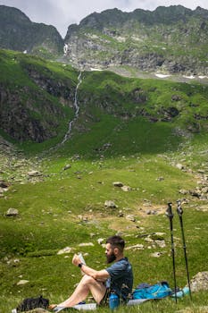 Man resting while hiking in the picturesque Romanian mountains, surrounded by lush greenery.
