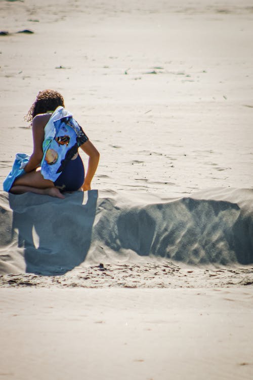 Woman in Blue Bathing Suit Sitting on Sand