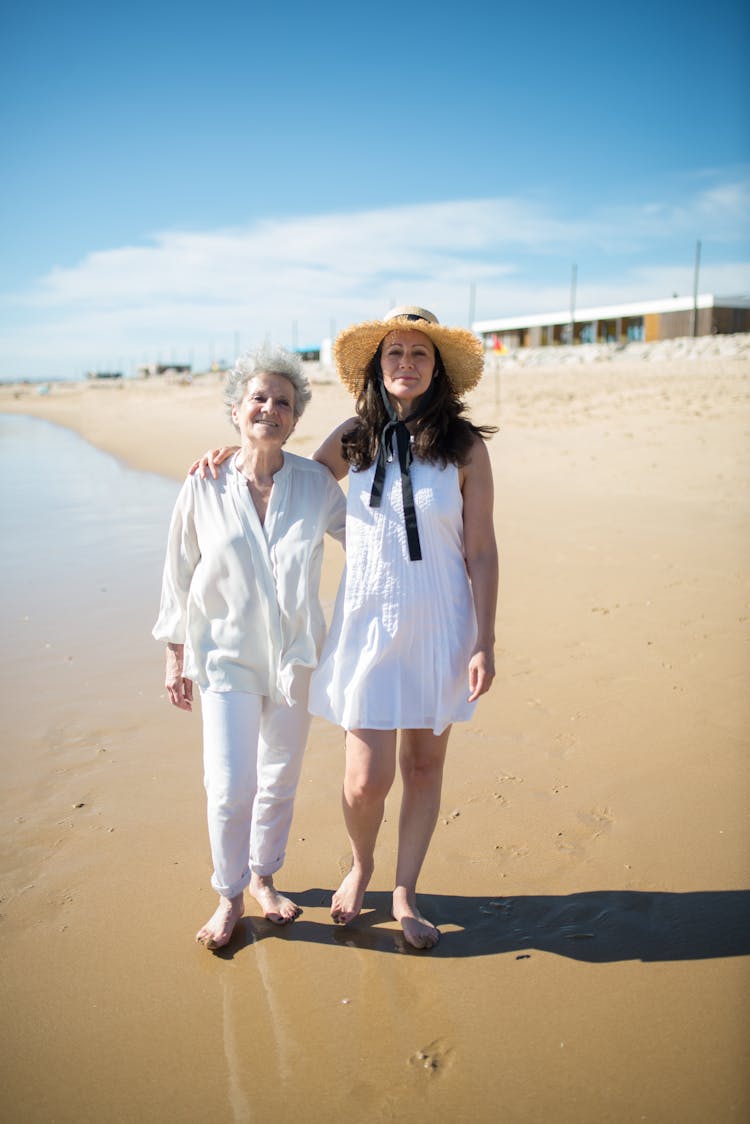 Mother And Daughter Walking On The Beach