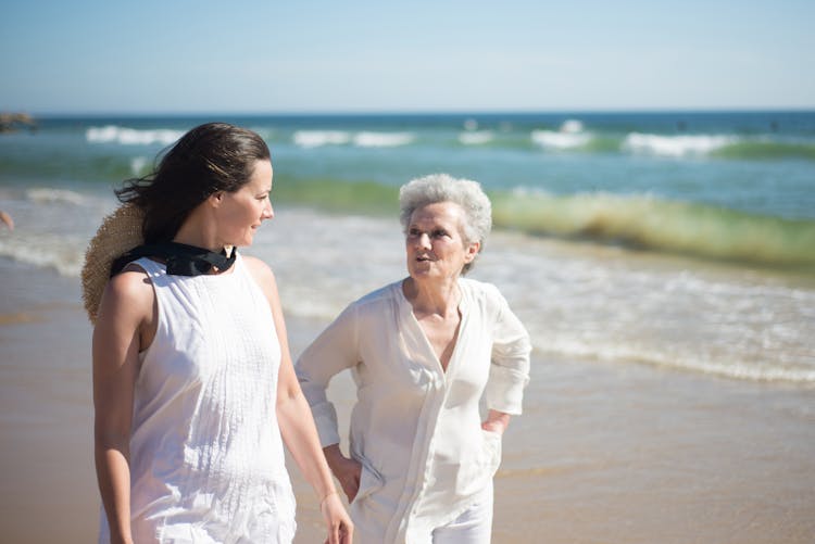 Mother And Daughter Walking On White Sand Beach