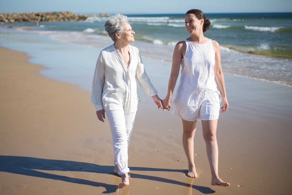 Free Woman in White Dress Holding the Hand of an Elderly Woman Stock Photo