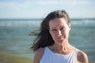 这是一幅宁静的肖像，描绘了一位妇女在海滩上享受阳光明媚、多风的日子