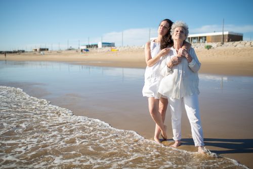 Free Mother and daughter share a joyful moment by the ocean on a sunny beach day. Stock Photo