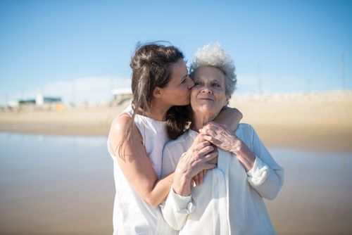 Free A touching moment of a daughter kissing her mother on a sunny Portuguese beach. Stock Photo