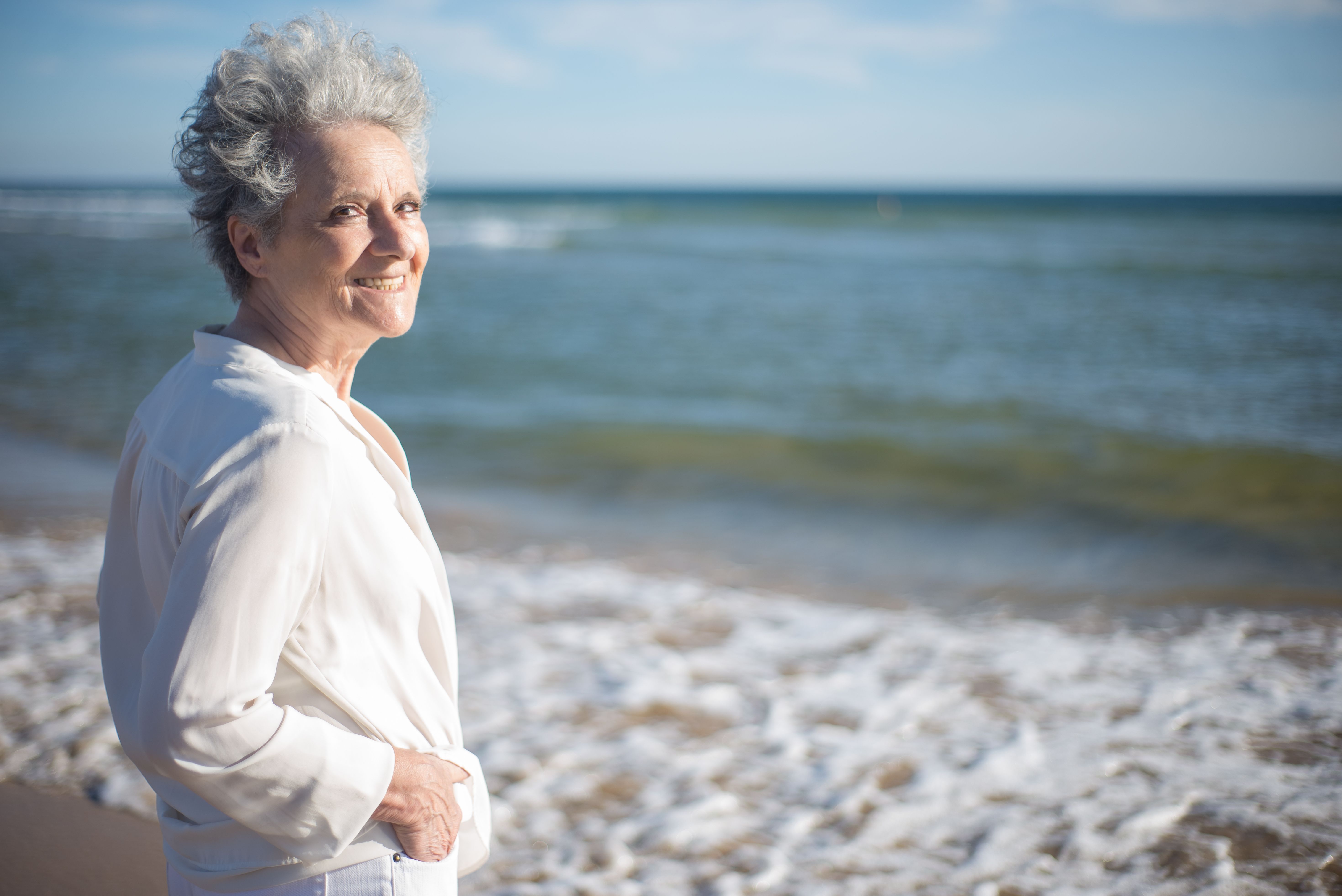 Joyful senior woman enjoying a sunny day by the Portuguese seaside.