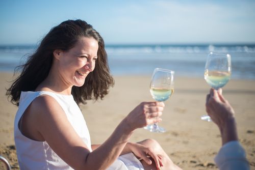 Free Two women toasting with white wine on a sunny beach in Portugal. Stock Photo