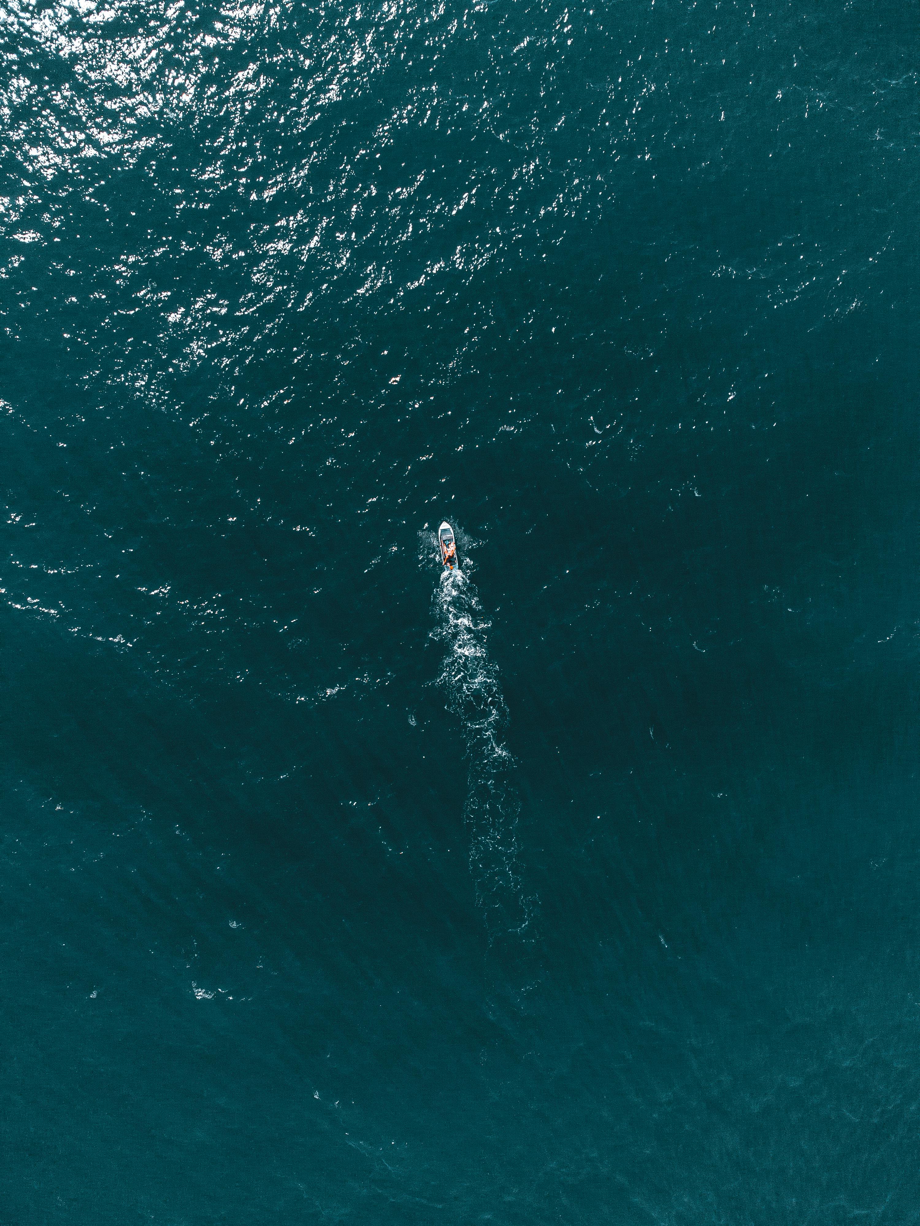Drone shot of a motorboat cruising through the expansive ocean waters.